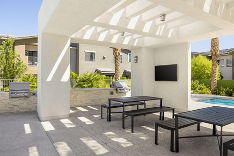 A patio with a black table and chairs under a white pergola.