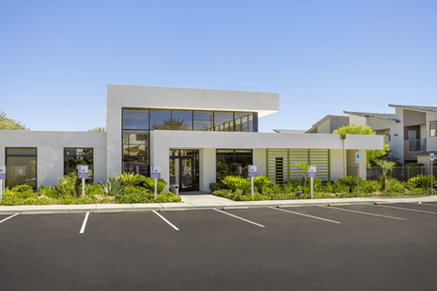 A modern building with a parking lot in front.