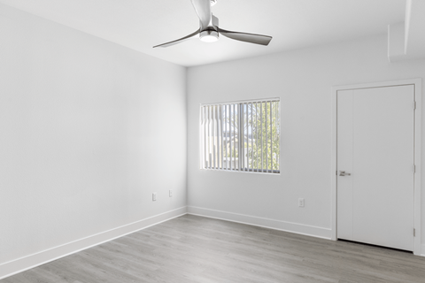 A room with a ceiling fan and a window with blinds.
