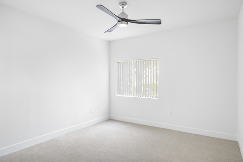A room with a ceiling fan and a window with blinds.