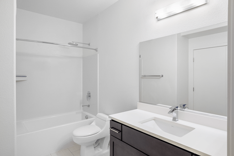A white bathroom with a toilet, sink, and mirror.