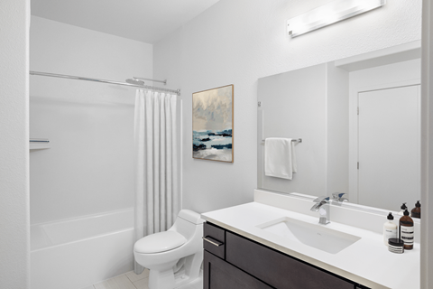 A white bathroom with a toilet, sink, and shower.
