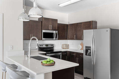 A modern kitchen with a white countertop and a refrigerator.