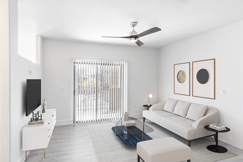 A living room with a white couch, a television, and a glass coffee table.