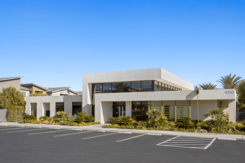 A modern building with a parking lot in front.