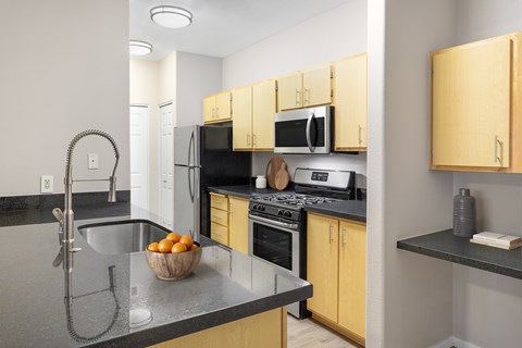 A kitchen with wooden cabinets and a black countertop.