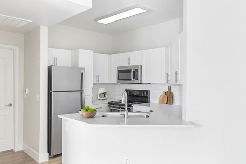 A kitchen with white cabinets and appliances.