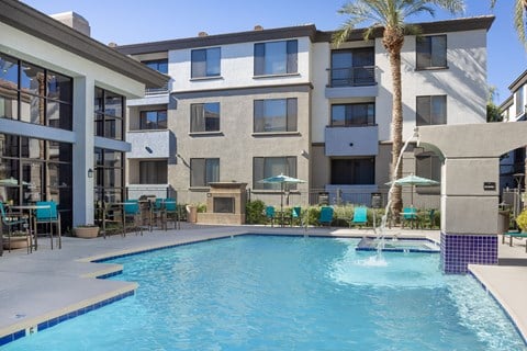 A swimming pool in front of a building with a palm tree.