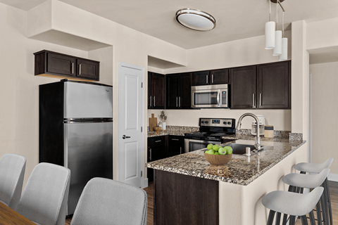 A kitchen with a granite countertop and a black refrigerator.