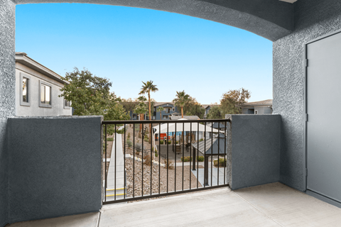 A balcony with a black railing overlooks a train track.