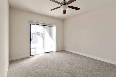 A room with a ceiling fan and carpeted floor.