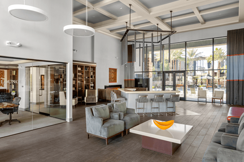 A modern living room with a glass wall and a grey sofa.