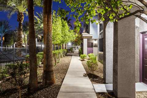A pathway with a sidewalk and a fence with a gate.