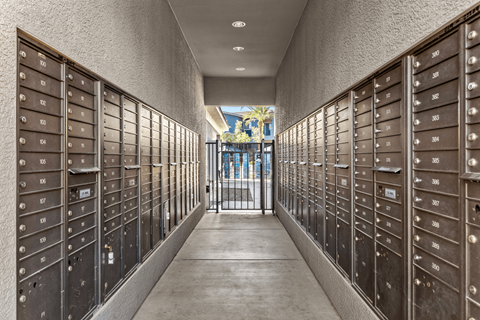 A long hallway with mailboxes on both sides and a door at the end.