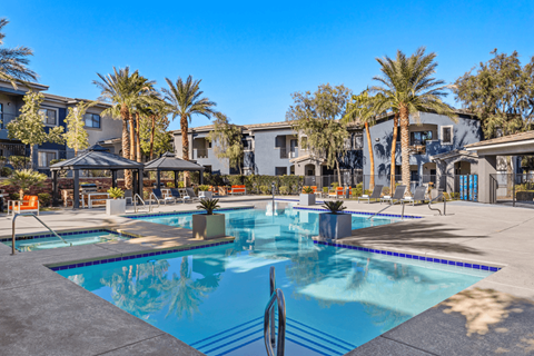 A swimming pool surrounded by palm trees and a sun umbrella.