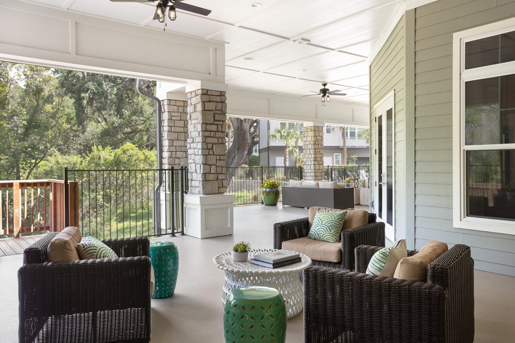 A patio with a black wicker sofa and a white table.