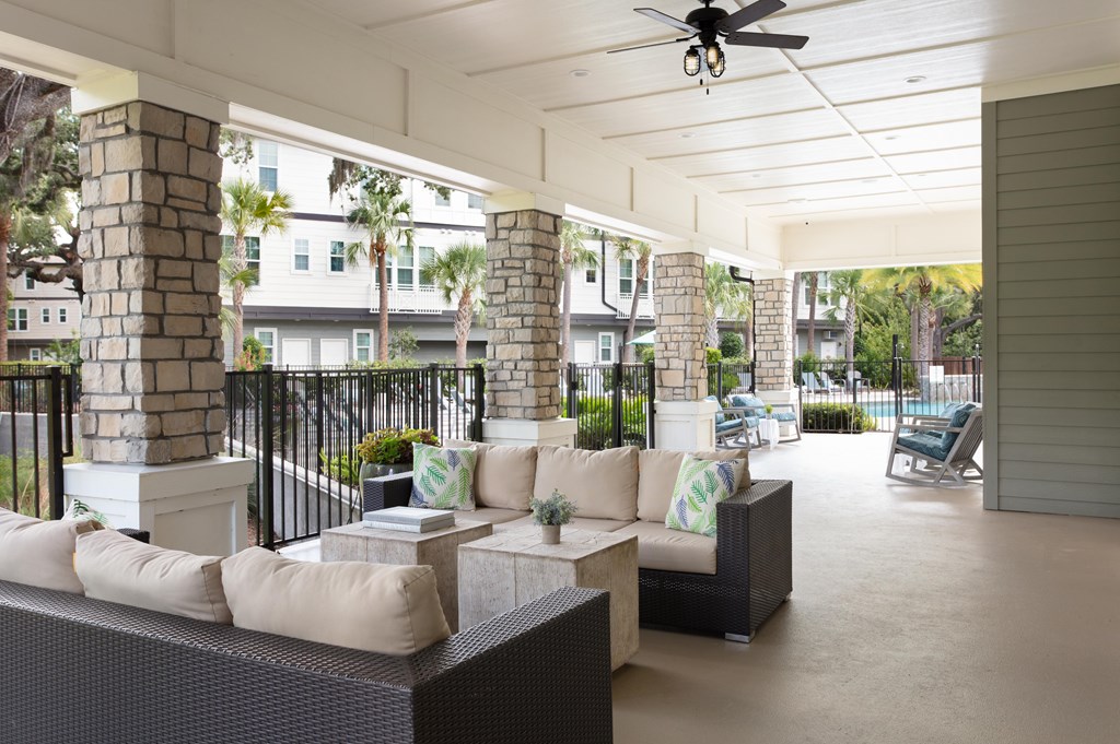 A patio with a black railing and a white ceiling fan.