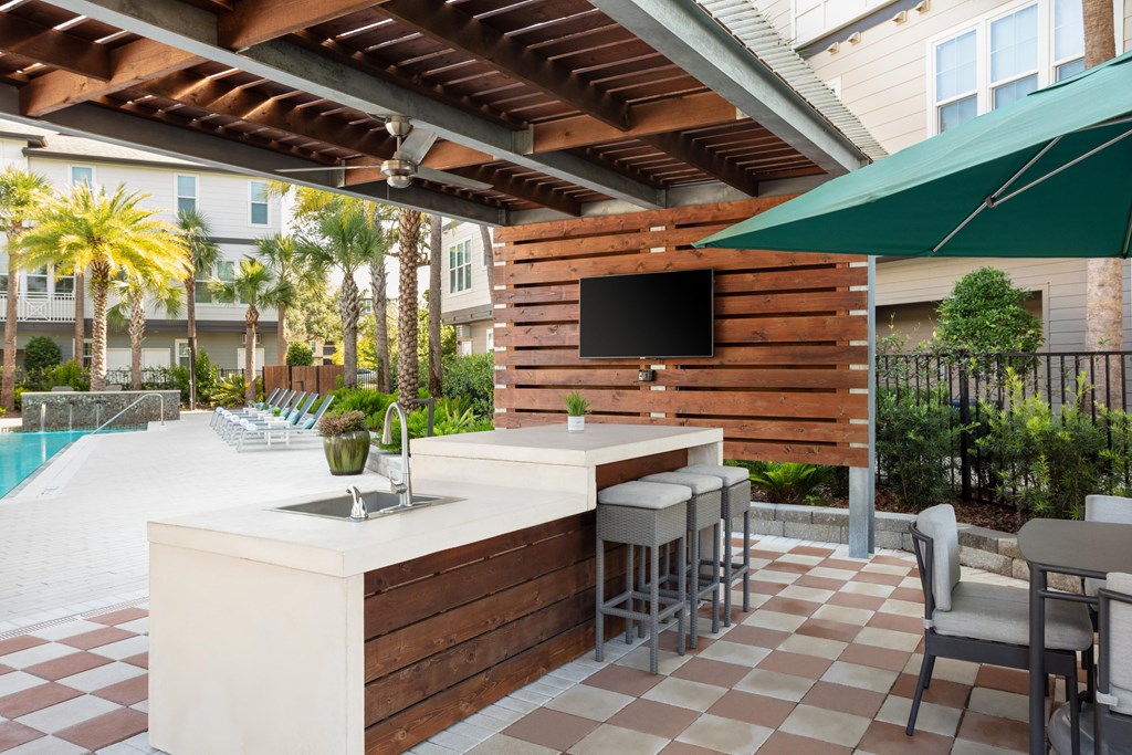 A patio with a bar and chairs under a roof.