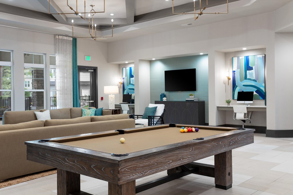 A pool table is in the middle of a room with a couch and a television.