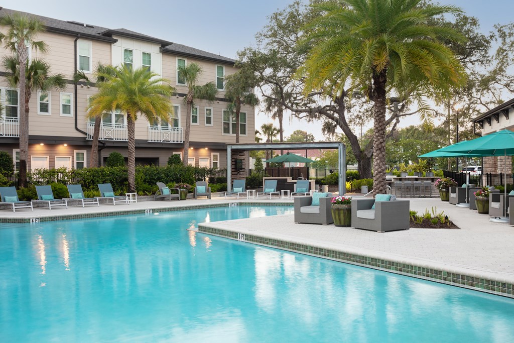 A swimming pool in front of a building with palm trees.