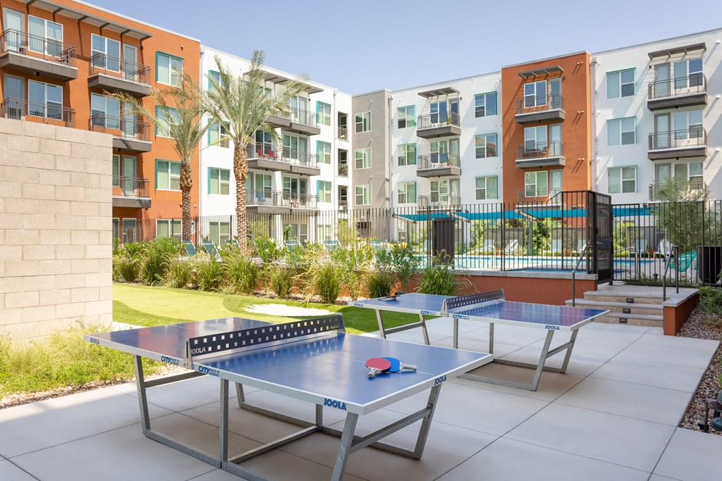 A ping pong table is in the middle of a courtyard with apartment buildings in the background.