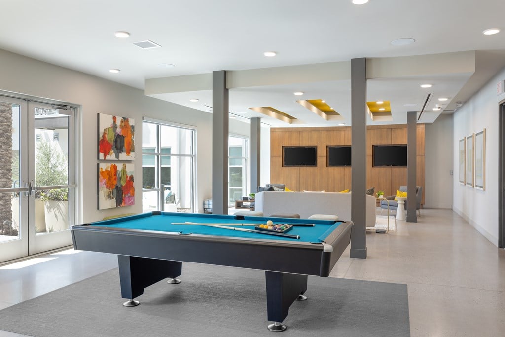 A pool table in a room with a wooden cabinet and a painting on the wall.