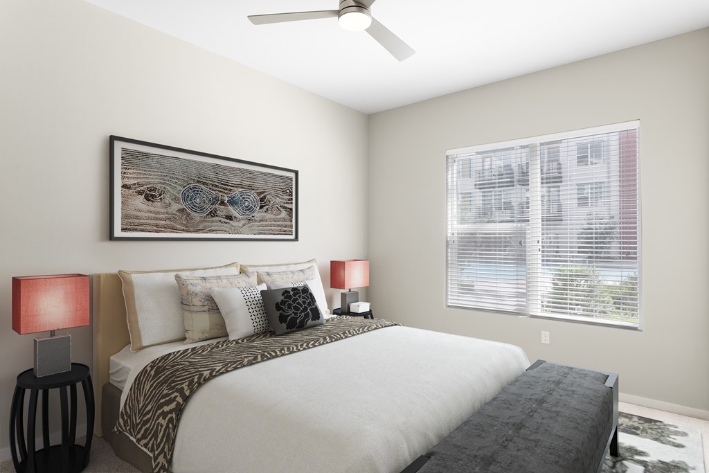 A bedroom with a large bed, two lamps, and a ceiling fan.