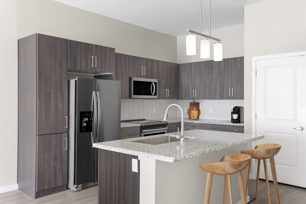 A kitchen with a refrigerator, microwave, and stove top oven.