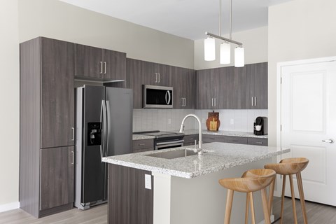 A kitchen with a refrigerator, microwave, and stove top oven.