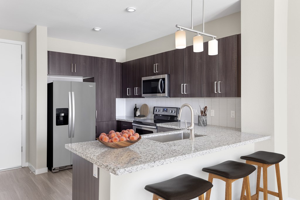 A kitchen with a granite countertop and stools.