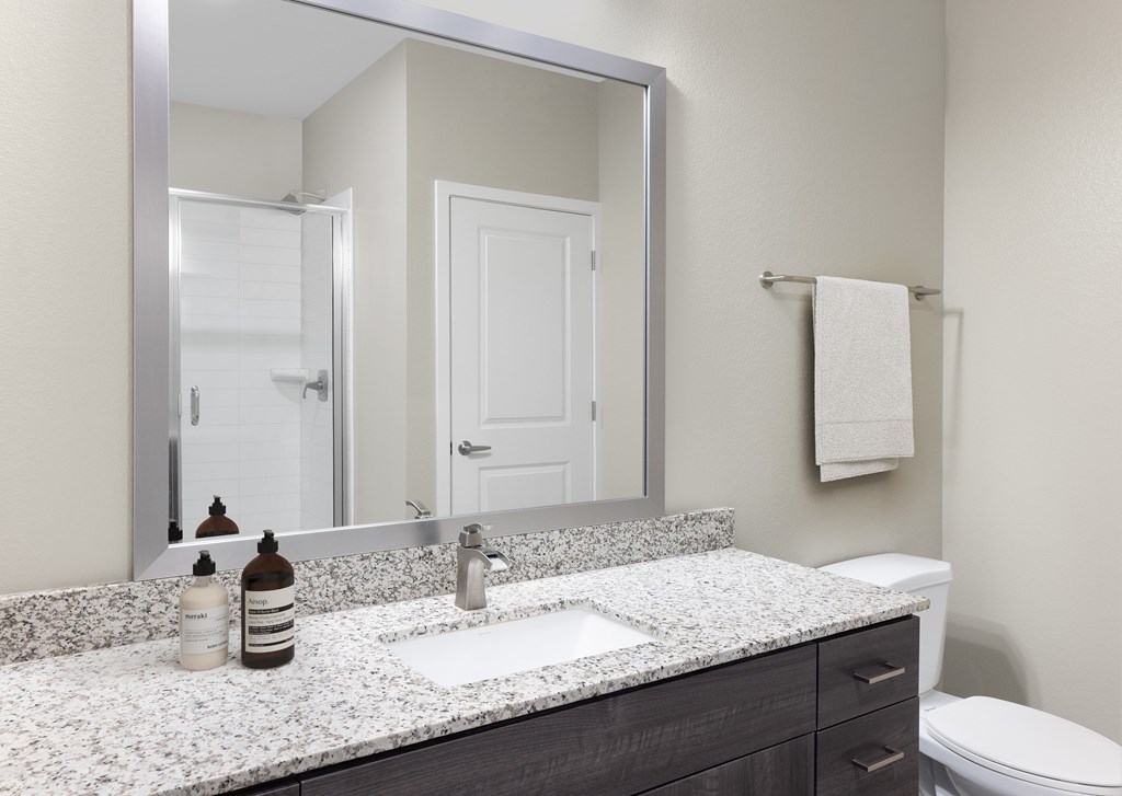 A bathroom with a white counter top and a toilet.