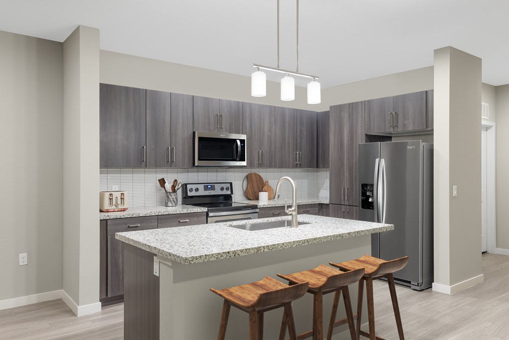 A modern kitchen with a granite countertop and wooden bar stools.