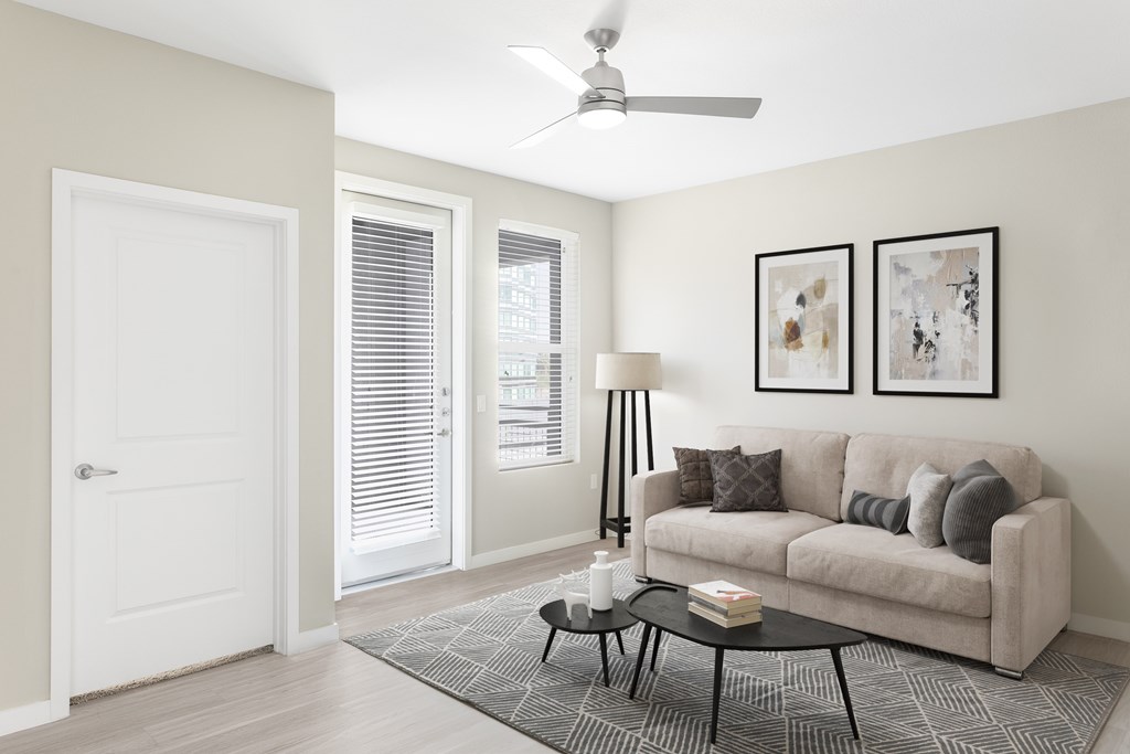 A living room with a couch, a table, and a ceiling fan.