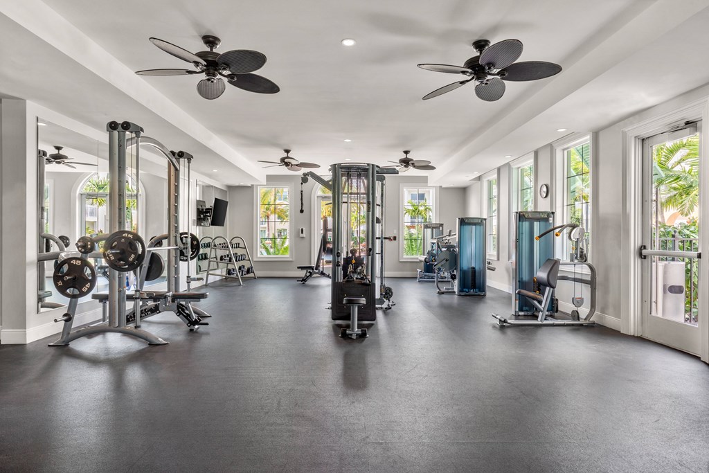 A spacious gym with a variety of equipment and a ceiling fan.