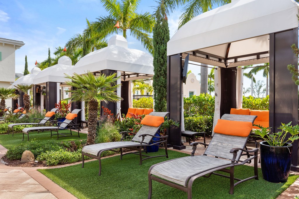 A white gazebo is surrounded by lawn chairs and plants.