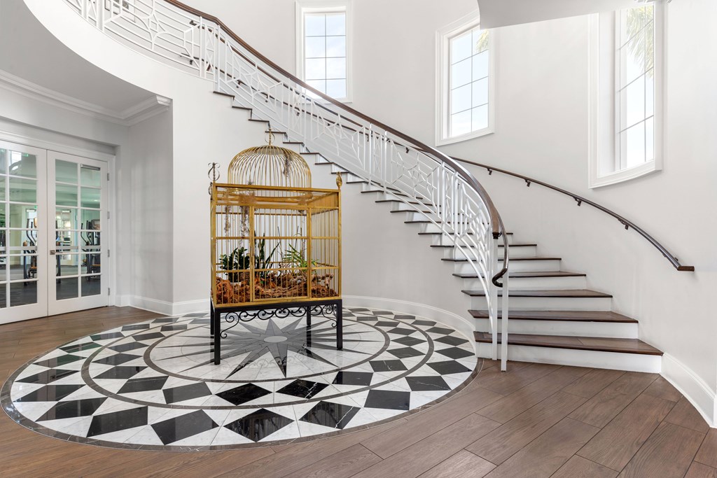A white staircase with a wooden banister and a birdcage on a circular rug.