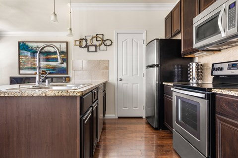 A kitchen with dark wood cabinets and black appliances.