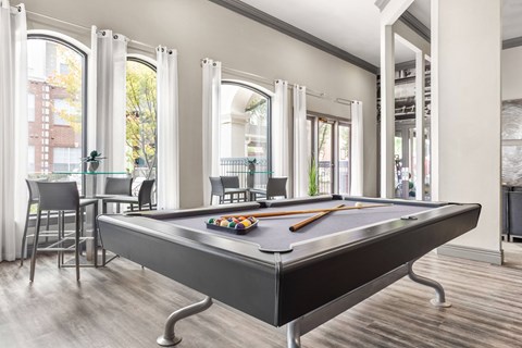A pool table is in the middle of a room with a lot of windows.
