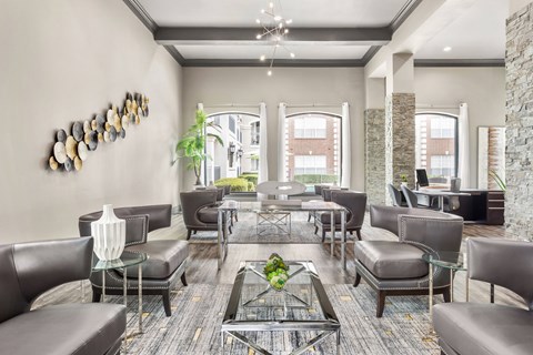 A modern living room with a glass coffee table and leather chairs.