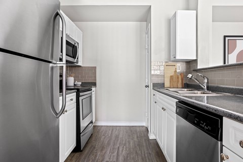 A modern kitchen with a stainless steel refrigerator and white cabinets.
