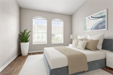 A bedroom with a large bed and a potted plant.