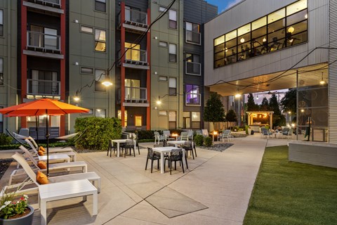 A patio area with tables and chairs is surrounded by apartment buildings.