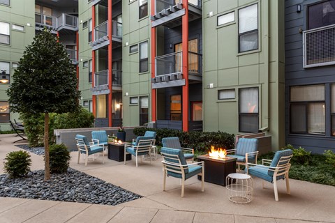 A patio with chairs and a fire pit in front of a building.