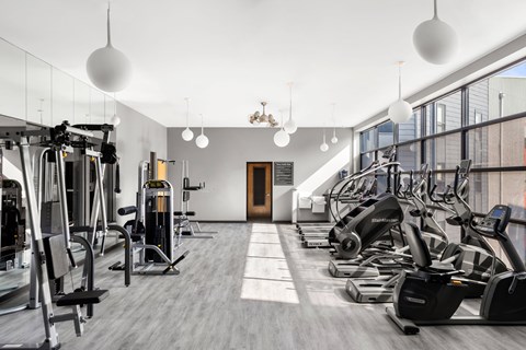 A gym with a variety of equipment including treadmills, weights, and exercise machines.