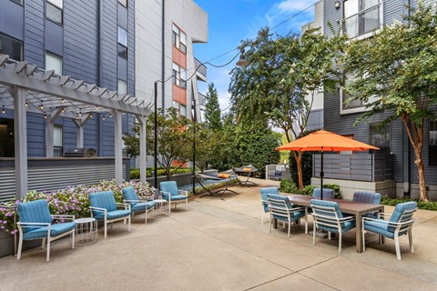 A patio with chairs and tables is surrounded by buildings.