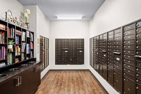 A room with a bookshelf, mailboxes, and a wooden floor.