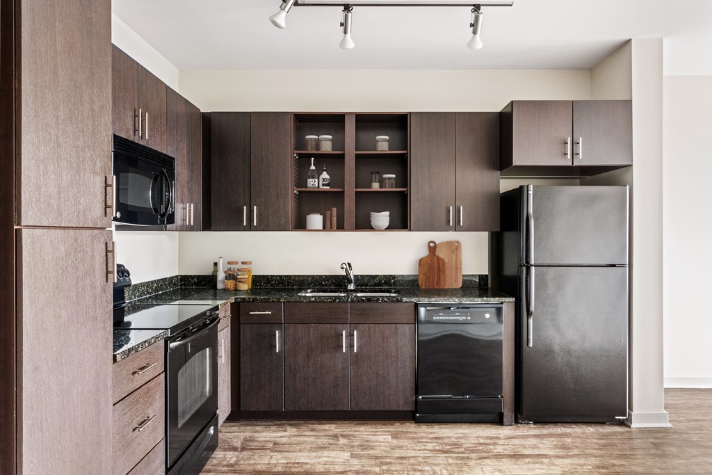 A kitchen with dark wood cabinets and black appliances.