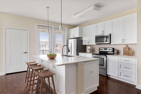 A kitchen with white cabinets and a wooden island.