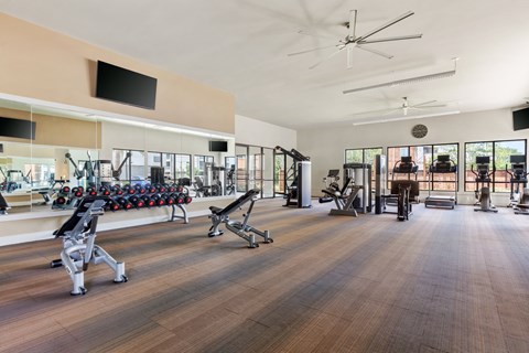A gym with a variety of equipment including weights and cardio machines.