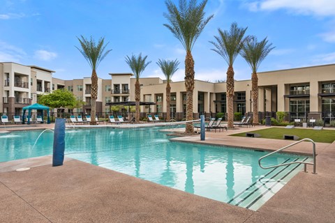 A swimming pool surrounded by palm trees and lounge chairs.